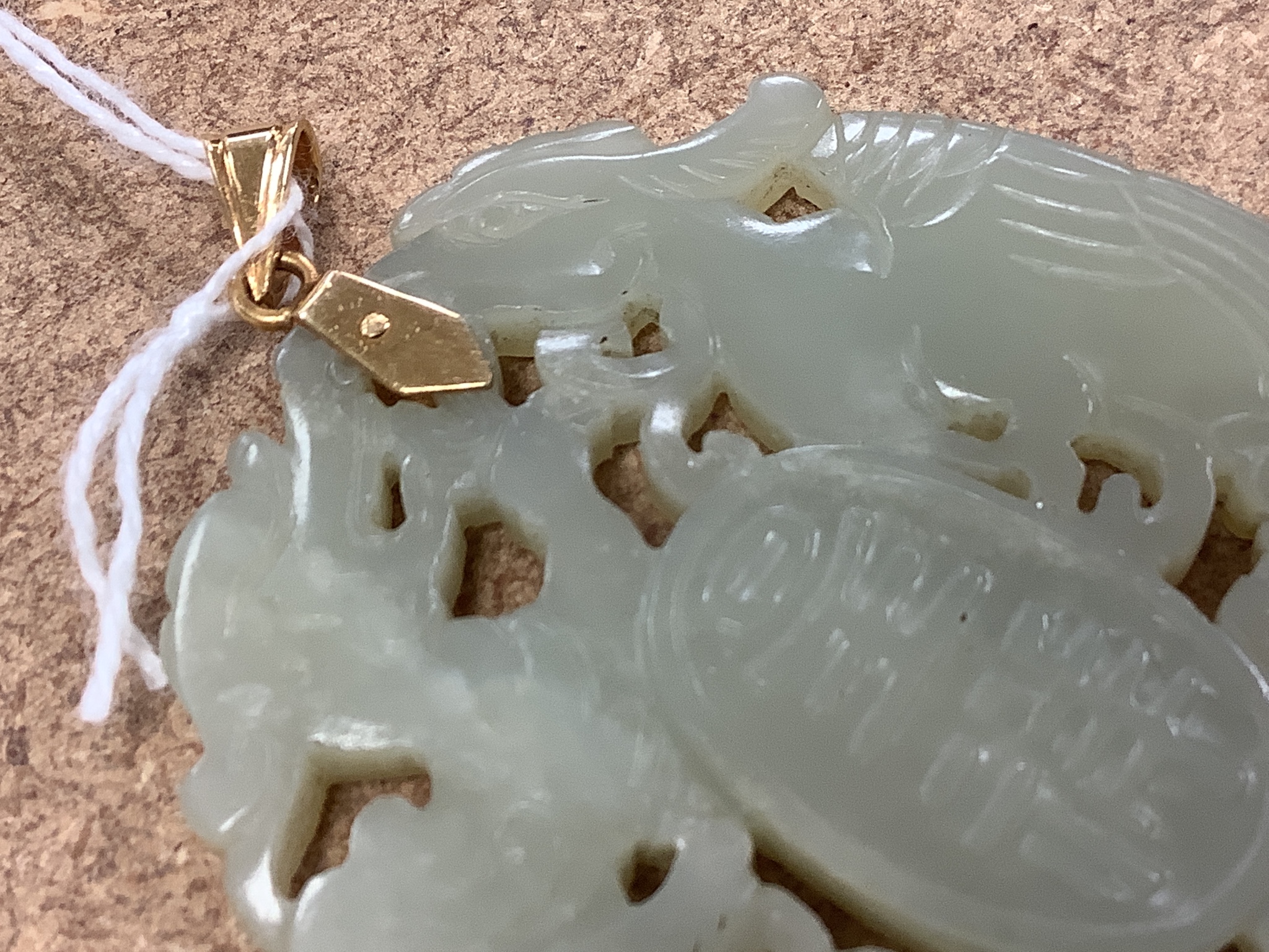 A Chinese yellow metal amounted jade pendant, 63mm, carved with dragons and character marks.